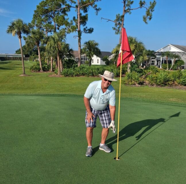 Tom Goldsmith reaches for his ball at the cup after his hole in one on No. 7