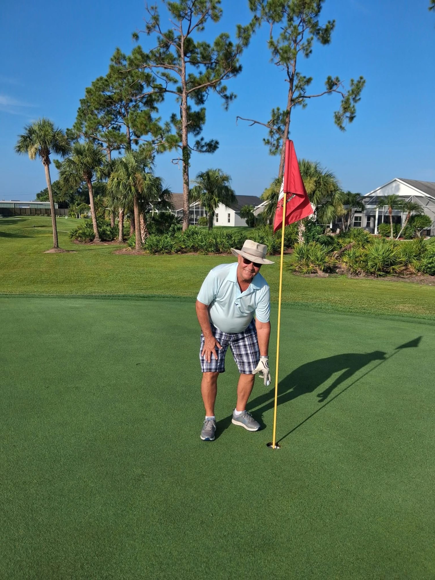 Tom Goldsmith reaches for his ball at the cup after his hole in one on No. 7