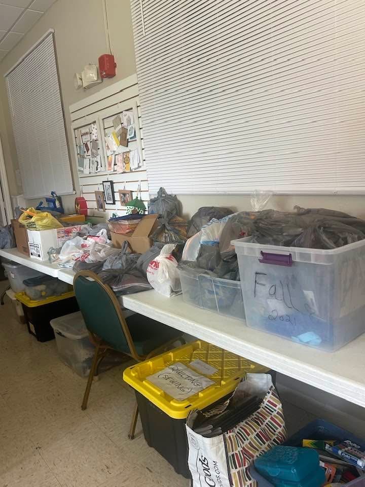 Table of collected school supplies in bins and bags ready for delivery