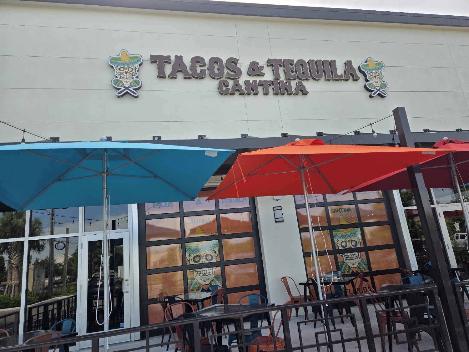 Tacos and Tequila Cantina storefront with turquoise and red patio umbrellas