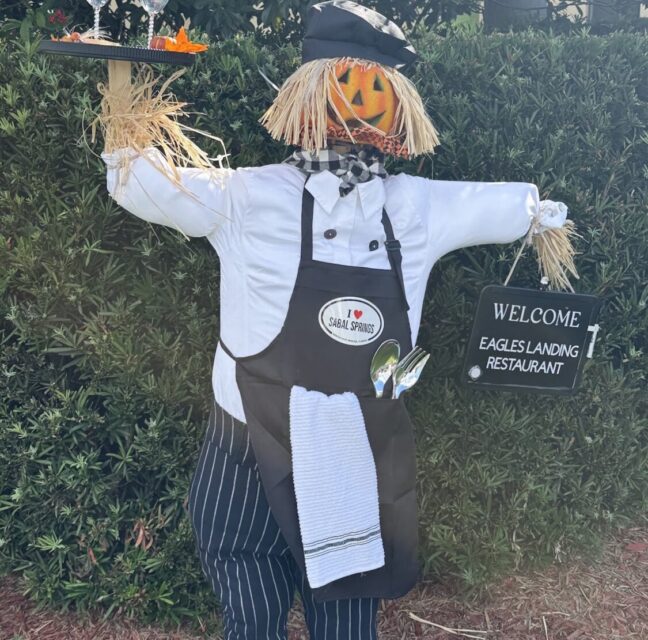 Chef scarecrow with a pumpkin head holding a tray for Eagles Landing Restaurant.