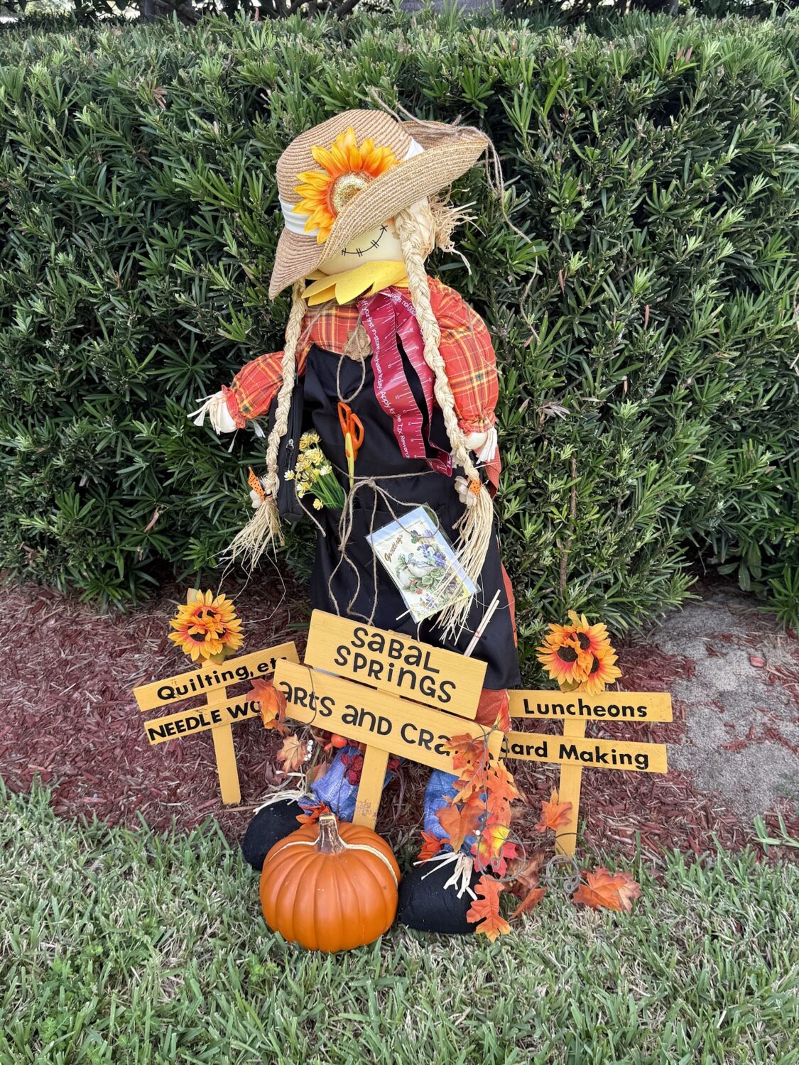 Arts and Crafts Committee scarecrow with sunflowers and activity signs.