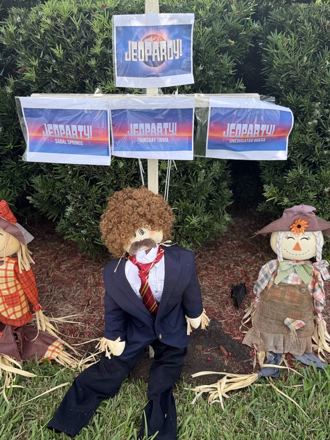 Scarecrow dressed as a game show host with Jeopardy signs.