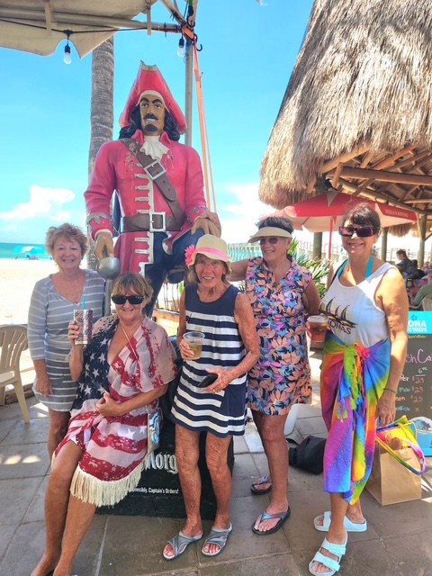 SunShine Singles members posing by a pirate statue at a beach bar.