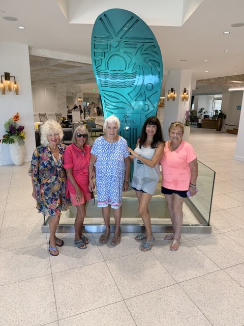 SunShine Singles members gathered by a surfboard display indoors.