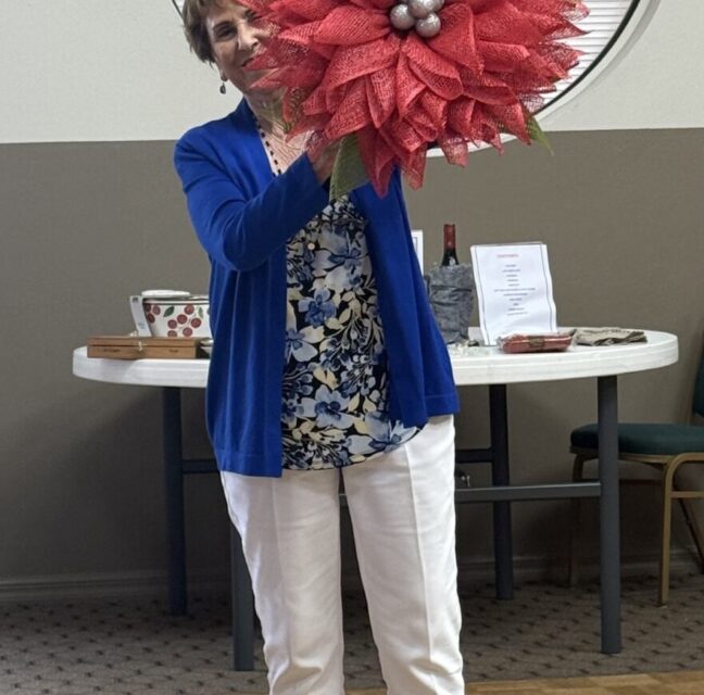 Jan Lambert holding a large red handmade fall wreath.