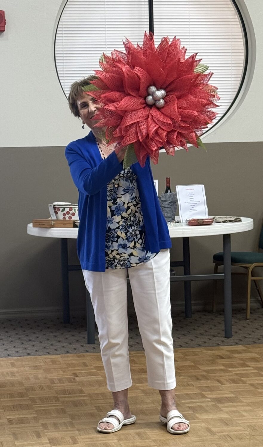 Jan Lambert holding a large red handmade fall wreath.