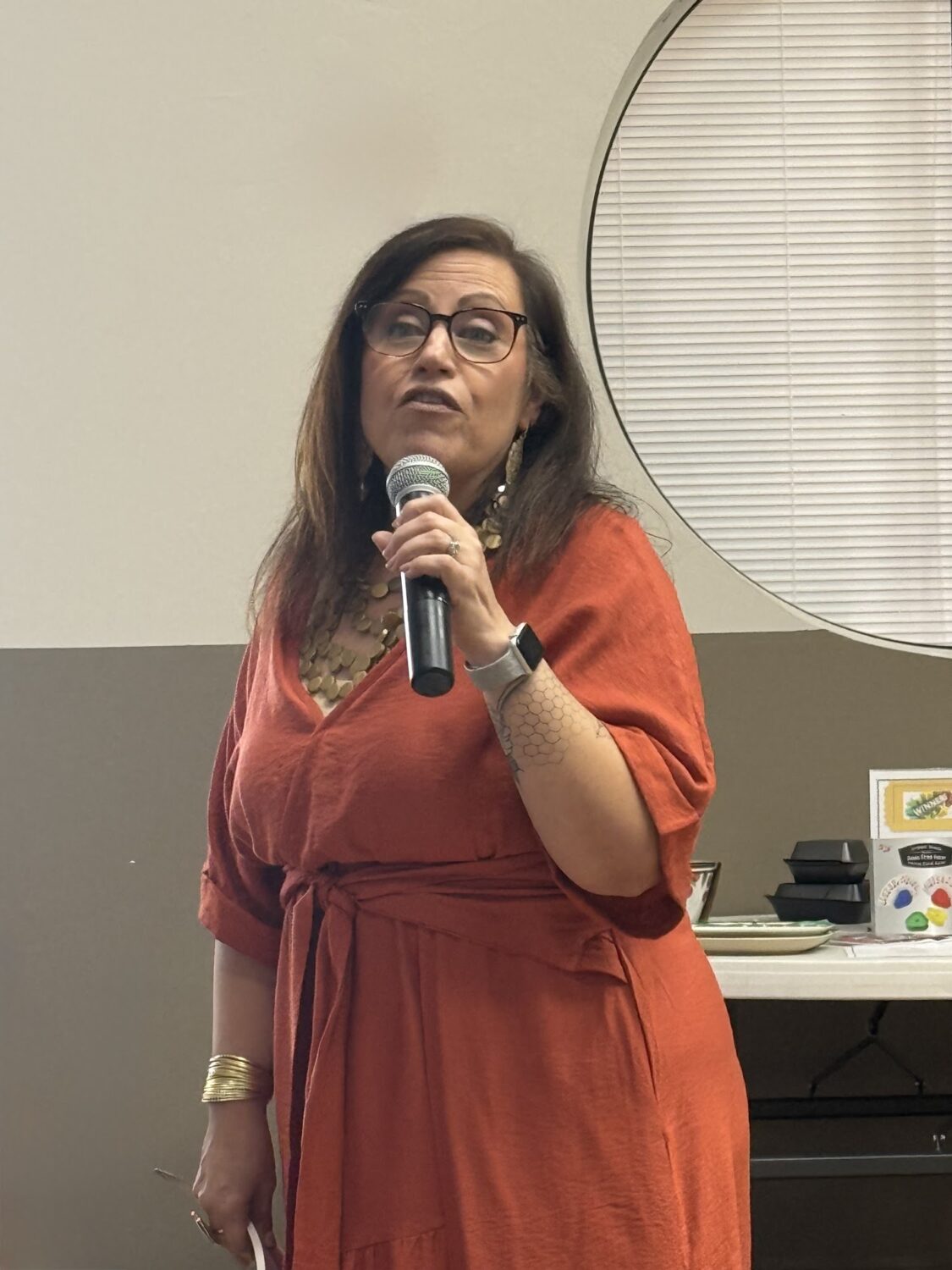 Tina Solomon speaking into a microphone at the Arts and Crafts luncheon.