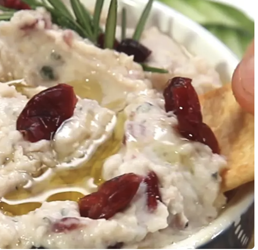 Bowl of white bean cranberry hummus drizzled with olive oil.